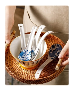 Detail of blue and white floral ceramic spoons set on a woven tray in a dining scene