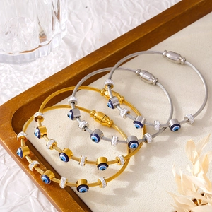 Titanium steel evil eye bangles with gold plating and rhinestones on a wood base