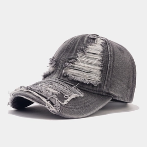 Detailed macro view of distressed denim baseball cap with frayed edges and ripped holes