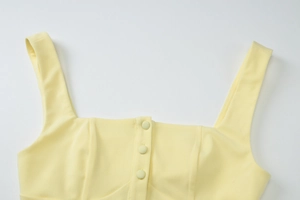 Detail of square neckline with matching buttons on light yellow woven tank top