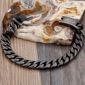 Makroansicht der grauen Titan-Panzerarmband-Kette auf Naturstein und Holzmaserung