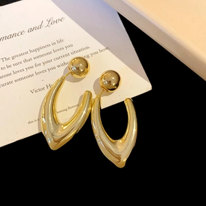 Detaillierte Makroansicht goldener U-förmiger Ohrringe auf einer dekorativen Karte