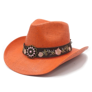 Detail of orange woven straw cowboy hat with floral embroidery and beaded metal accent