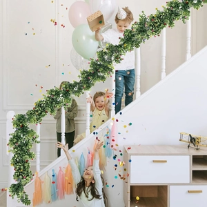 Artificial eucalyptus garland with colorful flowers draped on a staircase railing for decor
