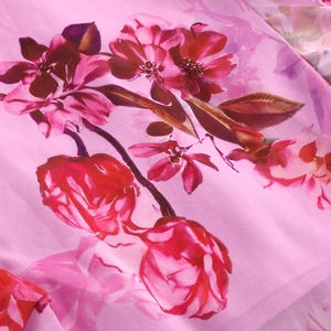 Close-up of pink floral chiffon fabric with delicate red and purple flower patterns