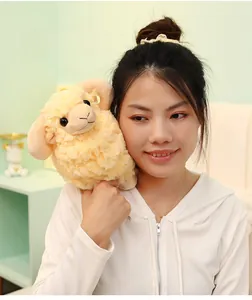 Close-up of a soft beige curly plush sheep toy held by a model in a cozy home setting