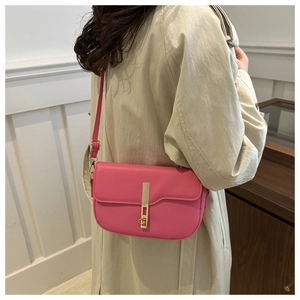 Pink PU leather saddle bag with gold metal buckle detail shown on a beige trench coat