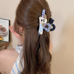 Pince à cheveux en tissu à carreaux bleus avec chien teckel en peluche sur modèle