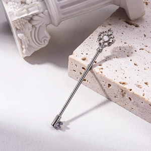 Edelstahl Industrial Piercing in Schlüsselform mit Opalherz auf beige Steinbasis
