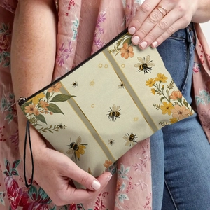 Portable beige honeybee and flower print makeup bag with black zipper and wrist strap