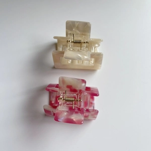 Close-up of square marble pattern hair claws with gold springs in beige and pink tones