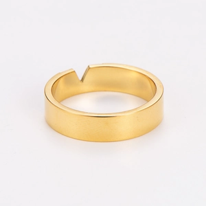 Macro shot of gold wide band ring featuring a distinctive V-shaped cutout on the edge