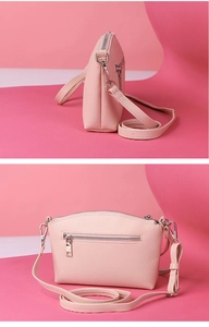 Detail view of pink textured leather crossbody bag with detachable strap and zipper
