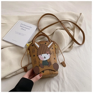Detailed view of mini bucket bag with cartoon rabbit charm on cream fabric background
