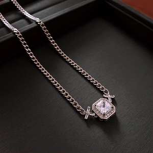 Détail du collier à maille gourmette argentée avec pendentif carré en zircon et croix