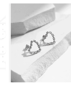 Macro detail of silver heart chain earrings with S925 sterling silver texture on stone