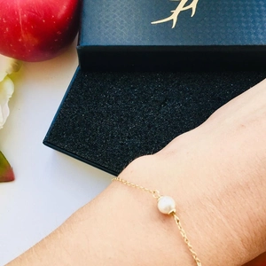 Elegantes goldenes Edelstahl-Armband mit weißer Perle am Handgelenk für Damen