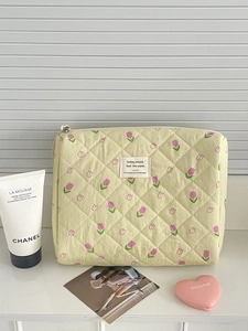 Detailed macro view of yellow quilted cotton makeup bag with purple tulip floral print