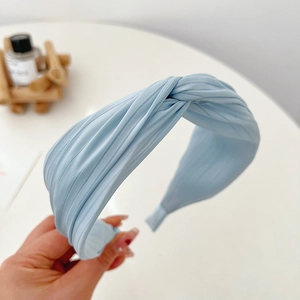 Close-up of light blue pleated headband with twist knot detail and elegant soft fabric texture