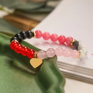 Detail of colorful agate bead bracelet featuring a gold heart charm and metal spacers