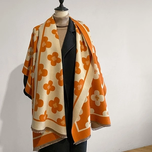 Detail of winter floral knit scarf with orange flower pattern and tassel edges on mannequin