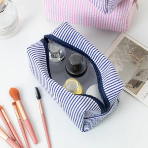 Top view of blue striped seersucker makeup bag showing spacious interior with toiletries