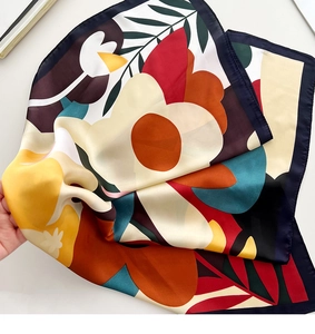 Close-up of silk scarf showing vibrant floral patterns and refined stitched edge