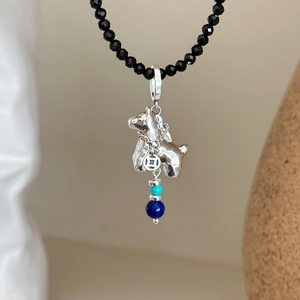 Black beaded necklace with silver terrier pendant and turquoise accents on cream background