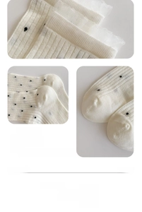 Detail of white bamboo fiber socks with black polka dots, lace trim, and reinforced toe