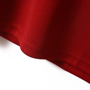 Detail of red knit mesh fabric showing the high-quality stitching on the polo shirt hem