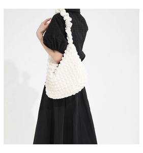 Detail shot of a white shoulder bag with unique bubble texture and soft ruffled strap