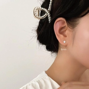 Close-up of 6mm zircon stud earrings in 925 sterling silver worn by a model