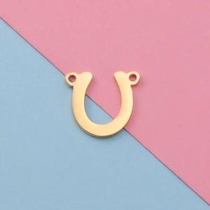 Close-up of golden U-shaped stainless steel jewelry connector on two-tone background
