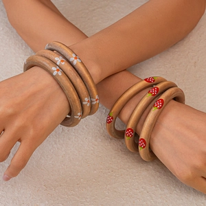 Detail of wooden bangles featuring hand-painted strawberry and floral patterns