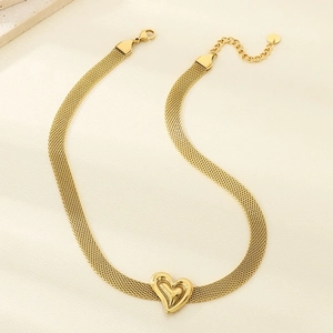 Detailed shot of golden woven mesh chain necklace with 3D heart pendant on soft fabric