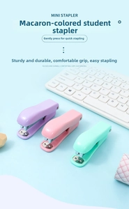 Overhead view of macaron colored mini staplers on a desk with a white keyboard