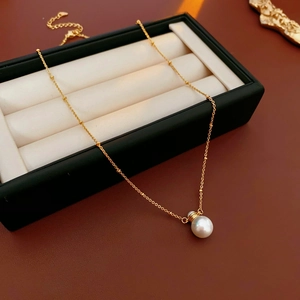Detailed close-up of a golden pearl necklace displayed inside a luxury black jewelry gift box