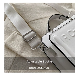Detail of adjustable strap and silver metal buckle on white tote bag with embossed text