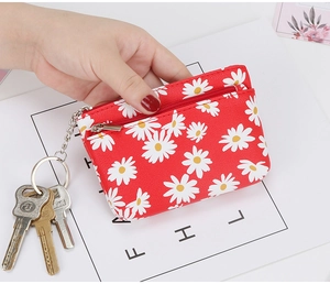 Detailed close-up of a red daisy floral leather coin purse with metal zipper and key ring