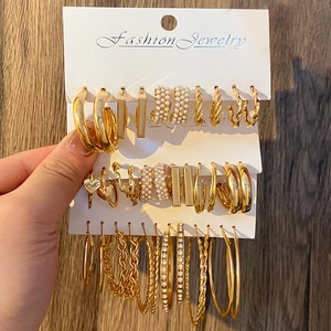 Golden earring set featuring pearls and rhinestones on a white display card