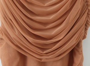 Gros plan sur le tissu en maille nude avec plis détaillés et texture drapée sur la robe