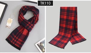 Detail of red and black plaid wool scarf featuring soft fringe edges and classic pattern