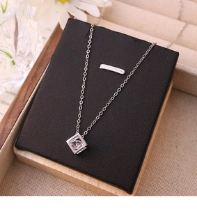 Macro detail of silver square zircon pendant on stainless steel chain on a display stand