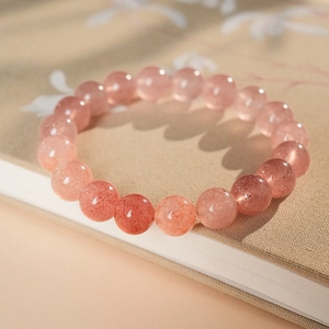Close-up of pink strawberry quartz beaded bracelet on a textured vintage book cover