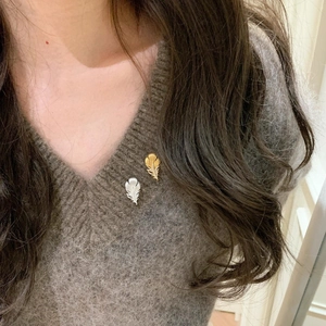 Exquisite gold and silver plated feather brooches with zircon on a brown knit sweater