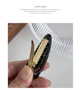 Detailed close-up of a marble pattern acetate hair clip with a golden metal clamp