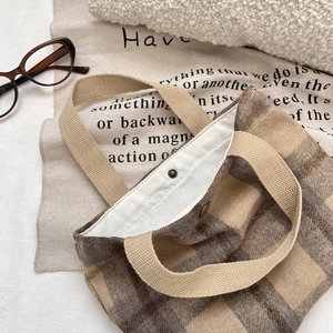 Detail of wool-like plaid tote bag with wide strap handle and metal snap closure