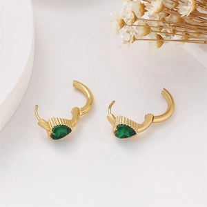 Detail of gold heart earrings with green zircon and textured metal finish on white tray