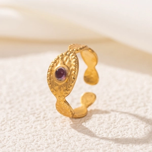 Macro detail of 18K gold ring featuring a purple stone and hand-hammered texture