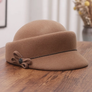 Close-up of wool equestrian hat with rhinestone bow detail on a rustic wooden surface